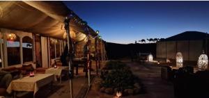 a tent with tables and chairs and lights at night at Maison Riad Tamarighte in Merzouga