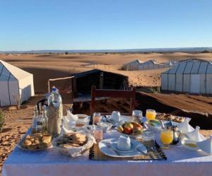 a table with food on it in the desert at Maison Riad Tamarighte in Merzouga