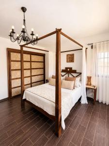 a bedroom with a four poster bed with a chandelier at Villa El Valle - Piscina climatizada in Tarajalejo +12 photos