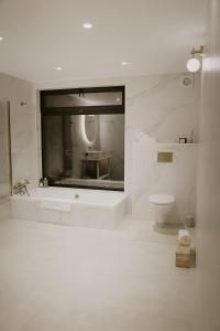 a white bathroom with a toilet and a sink at Nitaure Glamping in Viļums