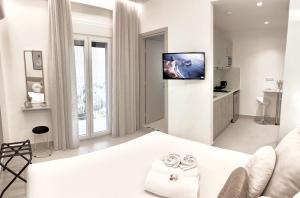 a white room with a bed and a flat screen tv at The Corfu Urban Stays in Ágios Rókkos