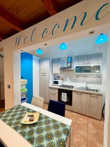 a kitchen with a welcome sign above a table at Casa Bella - Ortigia & Neapolis in Syracuse