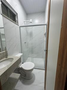 a bathroom with a toilet and a glass shower at University Suítes in Carmópolis