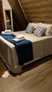 a large bed with blue and white pillows on it at Chalé A-Frame em Garanhuns - PE/ Rota do Frio in Garanhuns