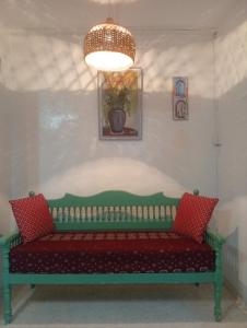 a green bench with red pillows in a room at Summer House in Dar Salah Bey