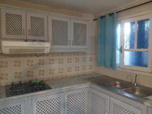 a kitchen with white cabinets and a sink and a window at Summer House in Dar Salah Bey