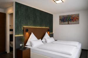 a bedroom with a white bed with a painting on the wall at Hotel am Hirschgarten in Filderstadt