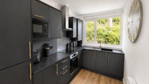 a kitchen with black cabinets and a clock on the wall at Bayview at the Port in Port Bannatyne