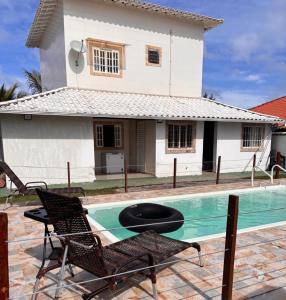 a villa with a swimming pool in front of a house at Casa Branca in Saquarema