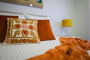 a bed with orange and white pillows on it at Dreamscape Villa in Ponta Delgada +35 photos