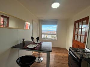 a kitchen with a counter with a table and a window at La Casita Austral in Punta Arenas