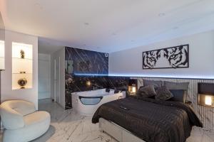 a bedroom with a tub and a bed and a chair at Blāck diamond spa in Mulhouse +15 photos