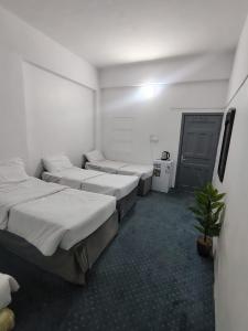 a room with four beds and a potted plant at Nour Taba Apartments in Medina