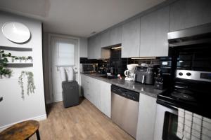 a kitchen with white cabinets and black appliances at Condo in St-Roch Downtown Quebec City in Quebec City