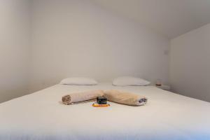 a white bed with two pillows and a wrench on it at L'Emeraude By Clem in Pélussin