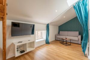 a living room with a couch and a flat screen tv at L'Emeraude By Clem in Pélussin
