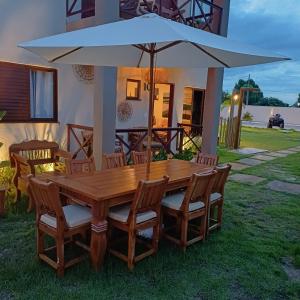 a wooden table with chairs and a large umbrella at Kite House Lençóis in Santo Amaro