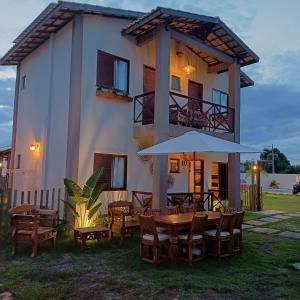 a house with a table and chairs and an umbrella at Kite House Lençóis in Santo Amaro