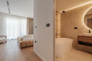 a bathroom with a bath tub and a bedroom at Nono Ban Boutique Hotel & Villas in Gornji Humac