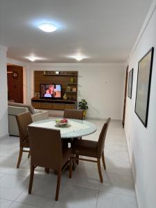 a dining room with a table and chairs and a tv at Solar Areia Preta 302 in Natal