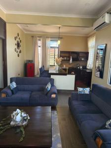 a living room with two blue couches and a kitchen at Nady Apartment in Dodoma