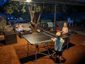 a boy and a girl playing ping pong on a ping pong table at Apartments Basina rated EXCEPTIONAL in Vrbanj