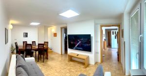 a living room with a couch and a tv on a wall at Apartment Sawetz - Ptuj in Ptuj
