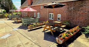 a patio with a wooden table and benches and flowers at The Boughton Peterchurch - Pub Grub & Bed in Peterchurch