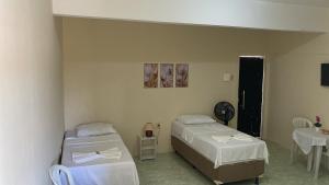 a room with two beds and a table and a clock at Hotel Renascer pojuca in Pojuca