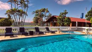 a swimming pool with chairs and a white fence at Chácara em Boituva-SP com piscina e churrasqueira in Boituva