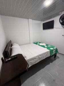 a small bedroom with a bed and a flat screen tv at Hostal Ruta Cafetera in La Tebaida +50 photos