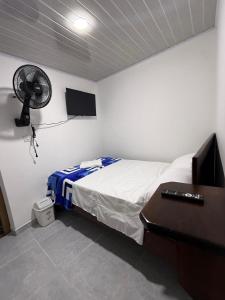 a bedroom with a bed with a fan and a desk at Hostal Ruta Cafetera in La Tebaida