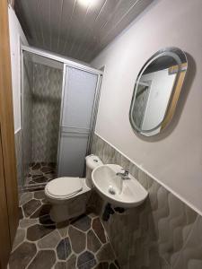 a bathroom with a toilet and a sink and a mirror at Hostal Ruta Cafetera in La Tebaida
