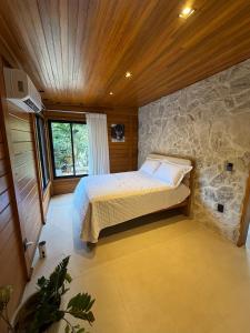 a bedroom with a bed and a stone wall at Chalé das Pedras - Domingos Martins in Domingos Martins +5 photos