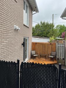 a backyard with a wooden deck with chairs and a fence at Studio Moderne Chic Gatineau Ottawa in Gatineau