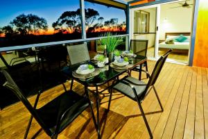 a dining table and chairs on a deck with a view of the sunset at Wine Down in Agnes Water