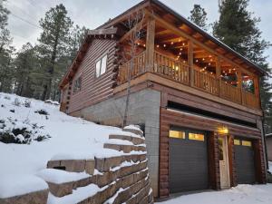 a log home with a deck and a garage in the snow at Cozy Forest Cabin with Hot Tub in Central Flagstaff in Flagstaff