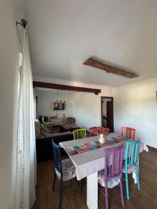 a dining room table with colorful chairs and a living room at El Mirador de Espadan in Alcudia de Veo