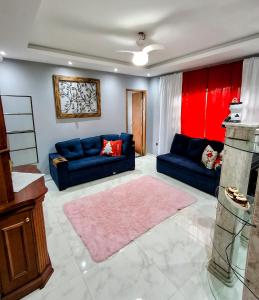 a living room with two blue couches and a pink rug at Casa no centro de Guapimirim, ar condicionado, piscina, churrasqueira, tranquilidade in Guapimirim