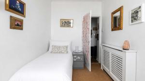 a white bedroom with a bed and a dresser at Williams Haven in Rothesay