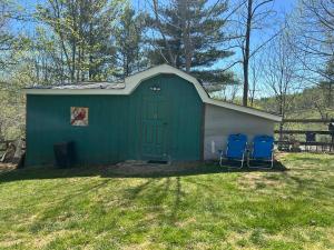 a green shed with two blue chairs in the yard at Swift Hollow Timeless Memories in Mountain City