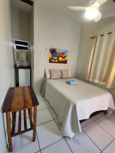 a bedroom with a bed and a table in it at Pousada Familiar Beberibe in Beberibe