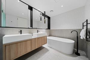 a bathroom with two sinks and a bath tub at The Eminence Apartments by CLLIX in Melbourne +71 photos