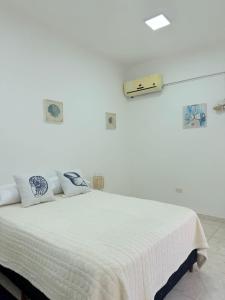 a white bedroom with a bed with white sheets and pillows at GuestHouse Encanto del Centro 4 in Encarnación +9 photos