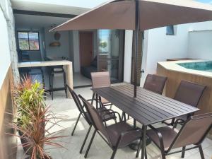 a table and chairs with an umbrella on a patio at Pé na areia, 3 suítes, terraço com piscina privativa in Camacari