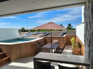 an outdoor patio with a table and an umbrella at Pé na areia, 3 suítes, terraço com piscina privativa in Camacari
