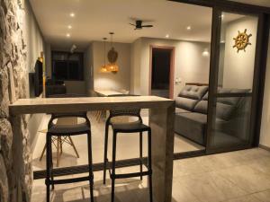 a kitchen and living room with a counter and stools at Pé na areia, 3 suítes, terraço com piscina privativa in Camacari