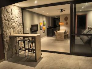 a living room with a table and a stone wall at Pé na areia, 3 suítes, terraço com piscina privativa in Camacari +14 photos