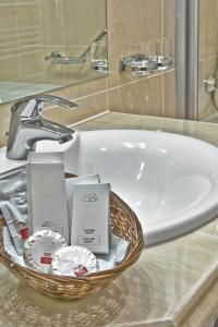 un lavabo con una cesta de artículos de tocador. en Hotel Citrin - Adults Only, en Brasov
