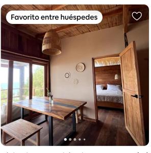 a room with a wooden table and a bed at Las tortugas bungalow in Vichayito